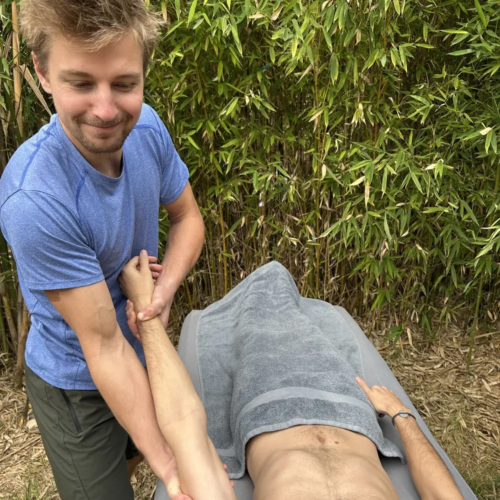 Massage sportif en extérieur avec une lecture précise du bras.